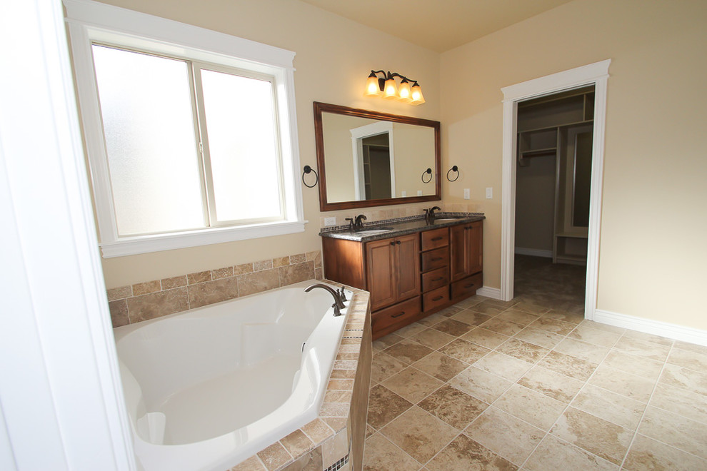 Inspiration for a medium sized classic ensuite bathroom in Boise with a built-in sink, flat-panel cabinets, medium wood cabinets, granite worktops, a corner bath, an alcove shower, a one-piece toilet, beige tiles, ceramic tiles, beige walls and ceramic flooring.