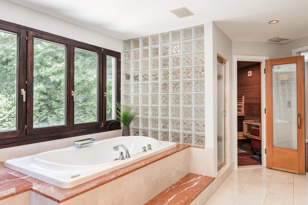 Cette image montre un grand sauna traditionnel avec une baignoire posée, une douche d'angle, WC séparés, un carrelage beige, un carrelage orange, du carrelage en pierre calcaire, un mur gris, parquet foncé, un sol marron et une cabine de douche à porte battante.