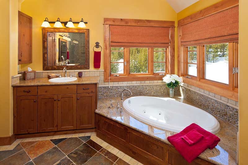 Свежая идея для дизайна: большая главная ванная комната в стиле рустика с фасадами в стиле шейкер, фасадами цвета дерева среднего тона, угловой ванной, галечной плиткой, желтыми стенами, полом из сланца, накладной раковиной и столешницей из гранита - отличное фото интерьера