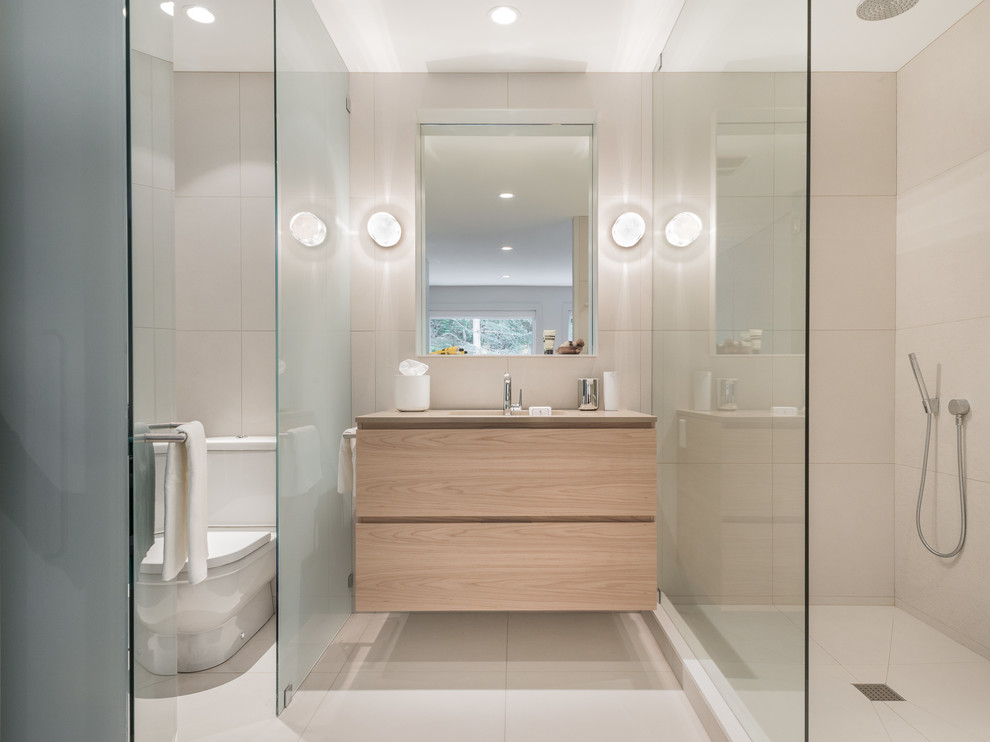 Cette photo montre une grande salle de bain principale moderne en bois clair avec un placard à porte plane, une douche ouverte, WC séparés, un carrelage beige, des carreaux de porcelaine, un mur beige, un sol en carrelage de porcelaine, un lavabo encastré et un plan de toilette en quartz modifié.