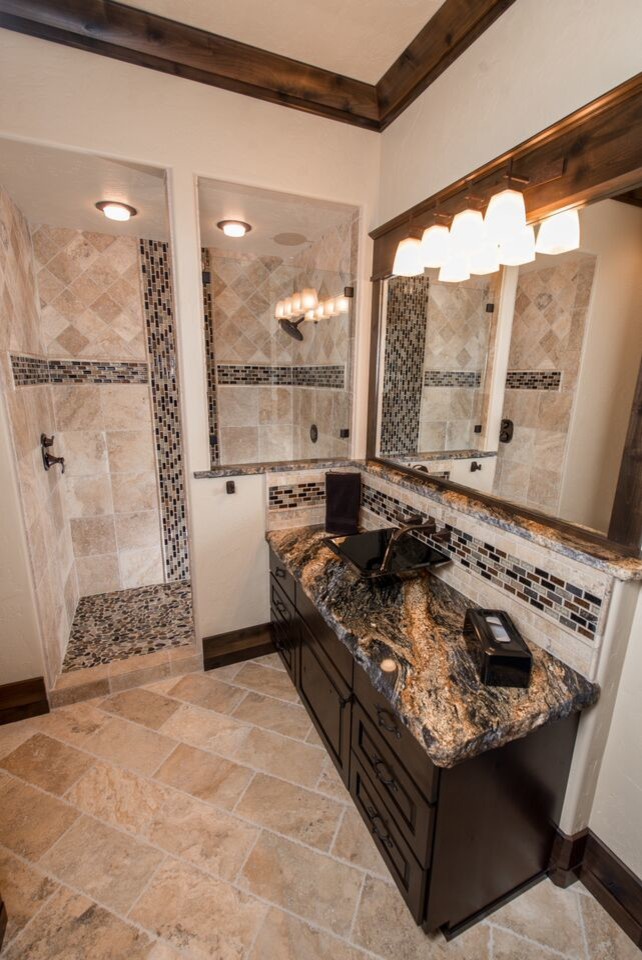 Design ideas for a large rustic family bathroom in Seattle with a vessel sink, raised-panel cabinets, dark wood cabinets, granite worktops, a walk-in shower, beige tiles, stone tiles, beige walls and travertine flooring.
