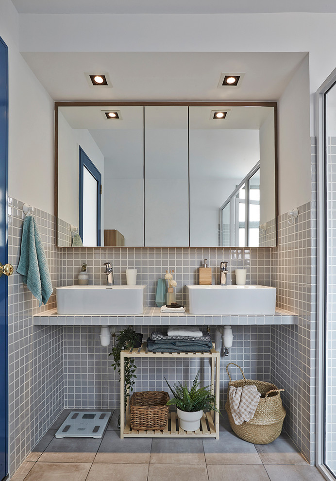 Modernes Badezimmer mit grauen Fliesen, Kieselfliesen, weißer Wandfarbe, Aufsatzwaschbecken, gefliestem Waschtisch, grauem Boden und grauer Waschtischplatte in Singapur