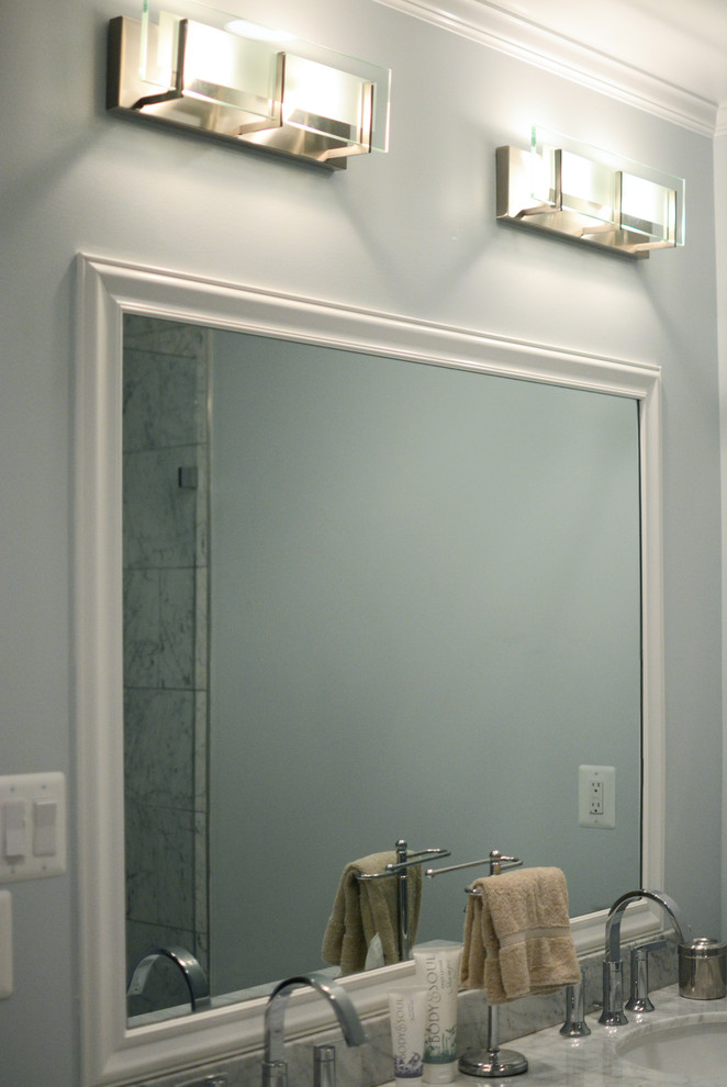 Cette photo montre une salle de bain principale chic de taille moyenne avec un lavabo encastré, un placard à porte plane, des portes de placard blanches, un plan de toilette en marbre, une douche double, WC séparés, un carrelage blanc, un carrelage de pierre, un mur bleu et un sol en carrelage de porcelaine.