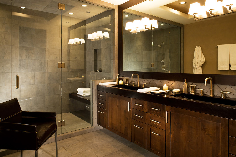 This is an example of a large contemporary sauna bathroom in Denver with flat-panel cabinets, medium wood cabinets, a corner bath, a one-piece toilet, black tiles, stone tiles, beige walls, slate flooring, concrete worktops, a built-in sink, an alcove shower, brown floors and a hinged door.