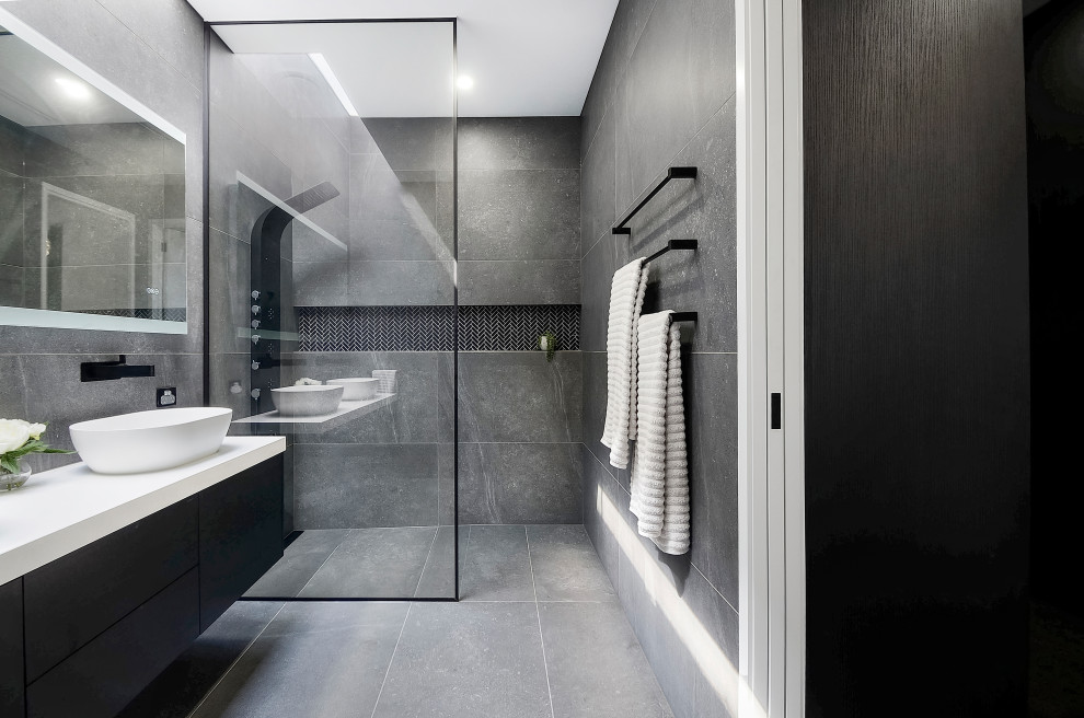 Idée de décoration pour une salle de bain design avec un placard à porte plane, des portes de placard noires, une douche à l'italienne, un carrelage gris, une vasque, un sol gris, un plan de toilette blanc, une niche, meuble double vasque et meuble-lavabo suspendu.