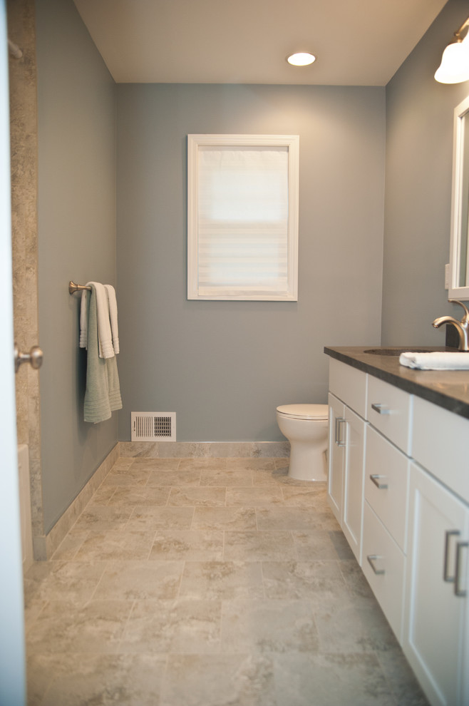 Bild på ett mellanstort vintage badrum, med skåp i shakerstil, vita skåp, beige kakel, stenkakel, blå väggar, klinkergolv i porslin, bänkskiva i kvarts, en toalettstol med separat cisternkåpa och ett undermonterad handfat