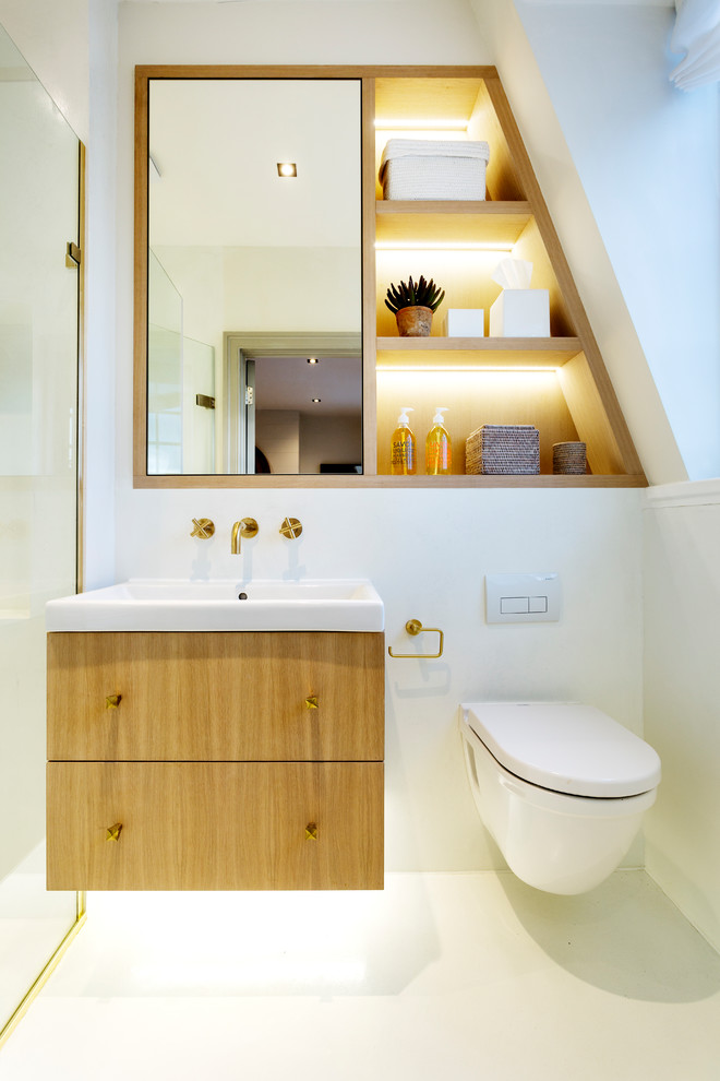 Réalisation d'une salle d'eau design en bois clair avec un placard à porte plane, WC suspendus, un mur blanc, un lavabo intégré et un sol blanc.