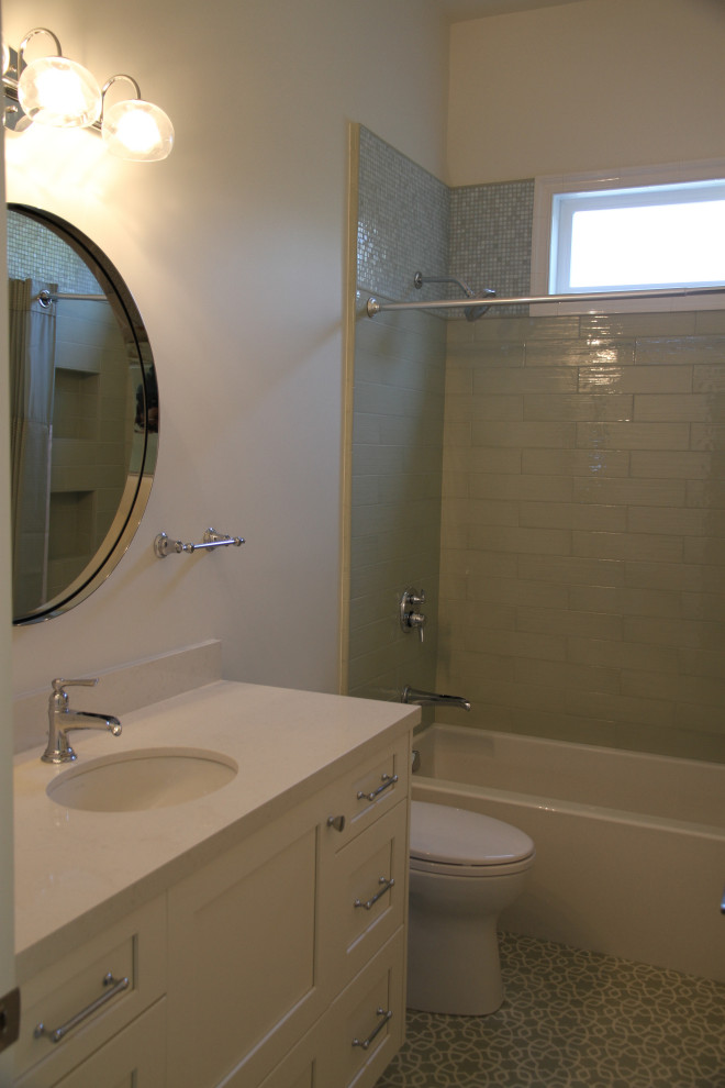 Inredning av ett klassiskt litet grå grått badrum för barn, med skåp i shakerstil, vita skåp, ett badkar i en alkov, en dusch/badkar-kombination, grön kakel, porslinskakel, vita väggar, cementgolv, ett undermonterad handfat, bänkskiva i kvarts, grönt golv, dusch med duschdraperi och en toalettstol med separat cisternkåpa