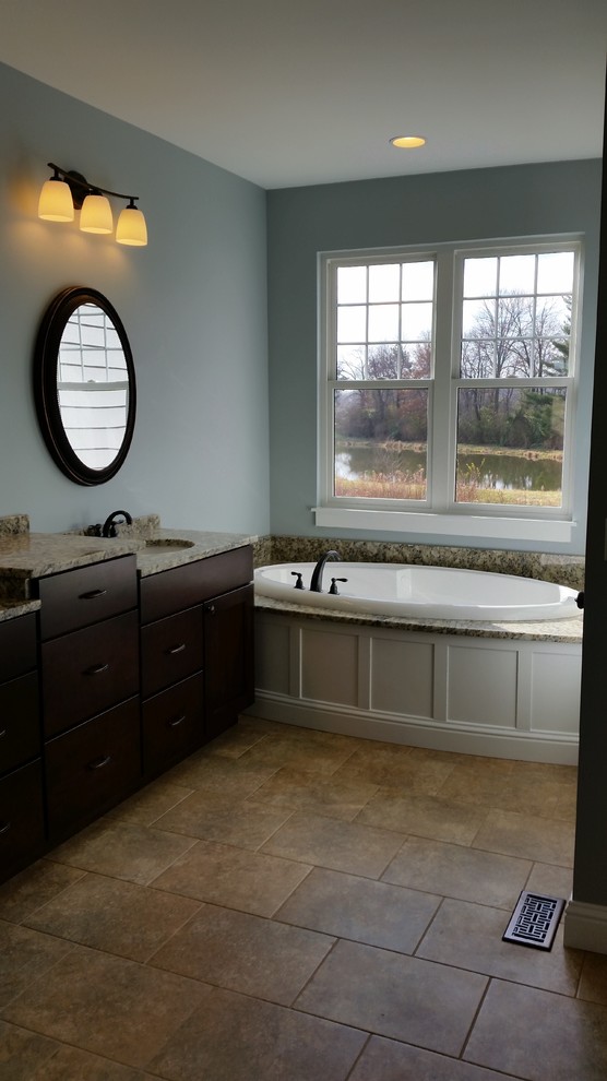 Esempio di una grande stanza da bagno padronale stile americano con ante di vetro, ante in legno bruno, vasca freestanding, pareti blu, lavabo sottopiano e pavimento beige