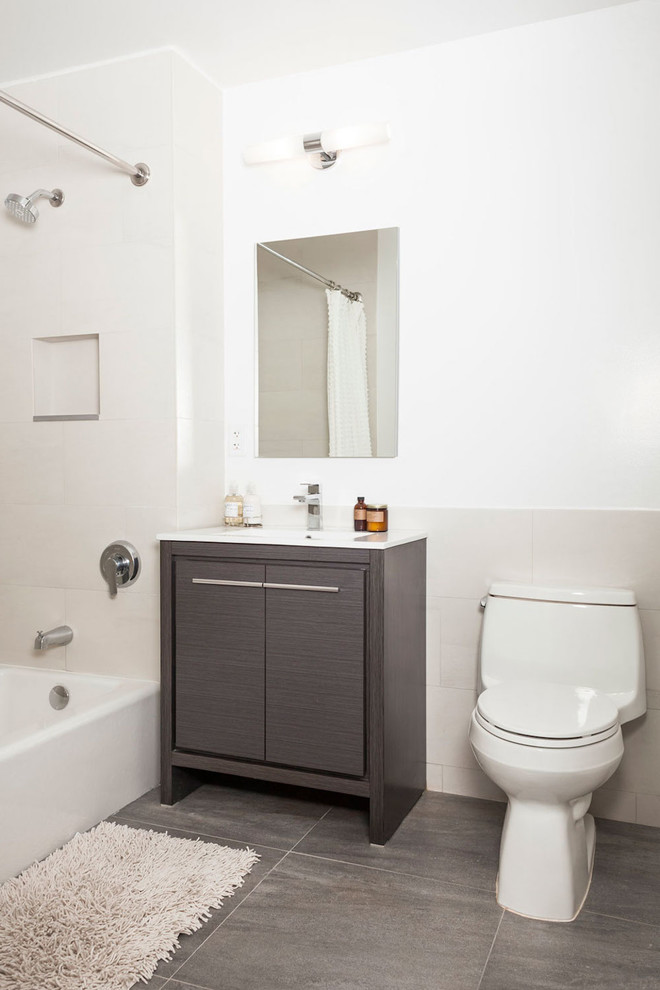 Exempel på ett litet klassiskt vit vitt badrum med dusch, med släta luckor, bruna skåp, en dusch/badkar-kombination, en toalettstol med hel cisternkåpa, beige kakel, porslinskakel, vita väggar, betonggolv, ett integrerad handfat, bänkskiva i akrylsten, grått golv och dusch med duschdraperi