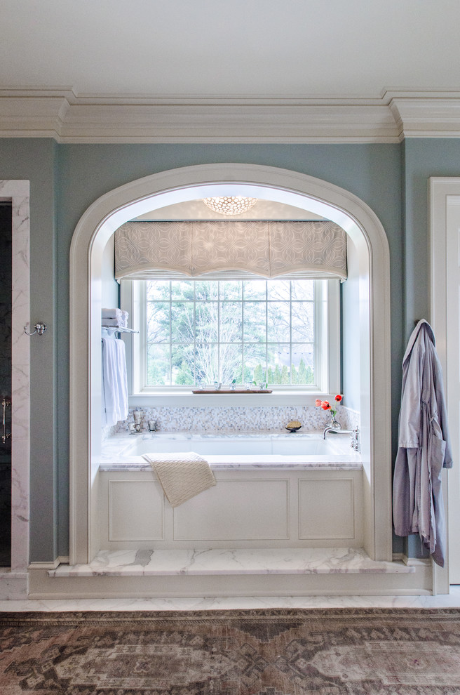 Idée de décoration pour une grande douche en alcôve principale tradition avec des portes de placard blanches, un plan de toilette en marbre, une baignoire posée, un carrelage gris, un carrelage de pierre, un mur bleu et un sol en marbre.