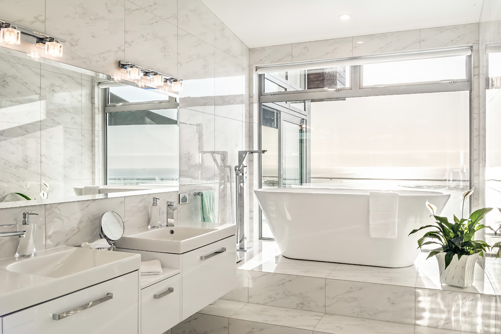 Immagine di una stanza da bagno con doccia contemporanea con ante lisce, ante bianche, vasca freestanding, piastrelle bianche, lavabo sospeso e pavimento bianco