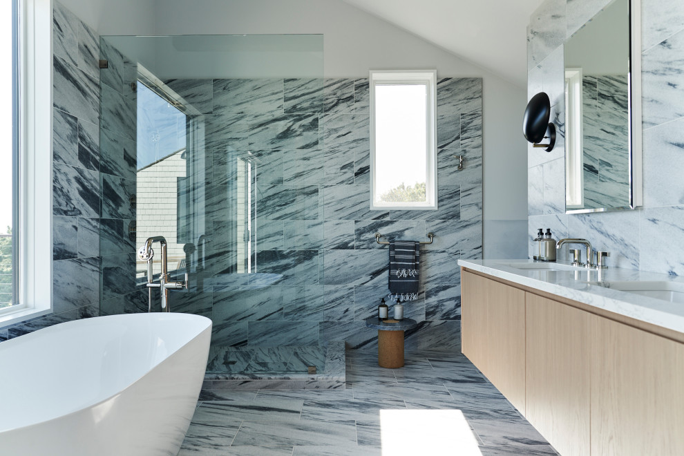 Bild på ett stort funkis vit vitt en-suite badrum, med släta luckor, skåp i ljust trä, ett fristående badkar, en vägghängd toalettstol, blå kakel, marmorkakel, marmorgolv, ett undermonterad handfat, marmorbänkskiva, blått golv och med dusch som är öppen