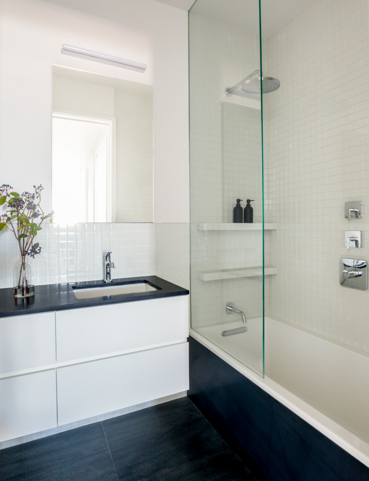 Bild på ett mellanstort funkis svart svart badrum med dusch, med släta luckor, vita skåp, ett badkar i en alkov, en dusch i en alkov, vit kakel, glaskakel, vita väggar, ett nedsänkt handfat, svart golv och med dusch som är öppen