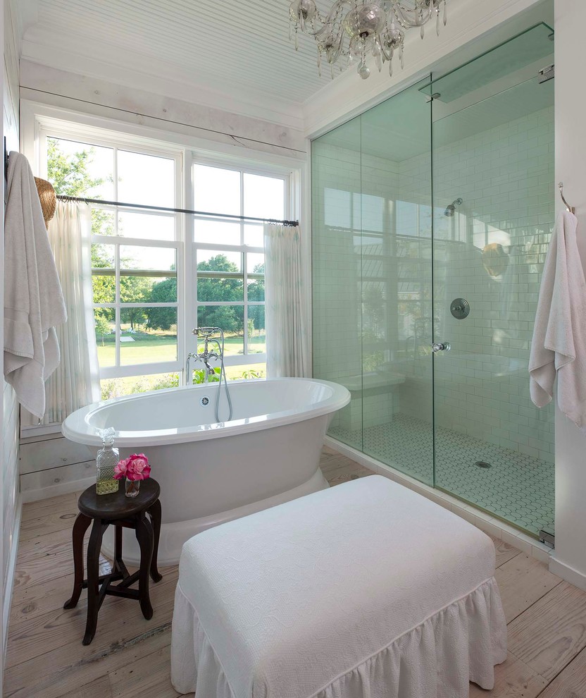 Ejemplo de cuarto de baño campestre con bañera exenta, ducha empotrada, baldosas y/o azulejos blancos, baldosas y/o azulejos de cemento y suelo de madera clara