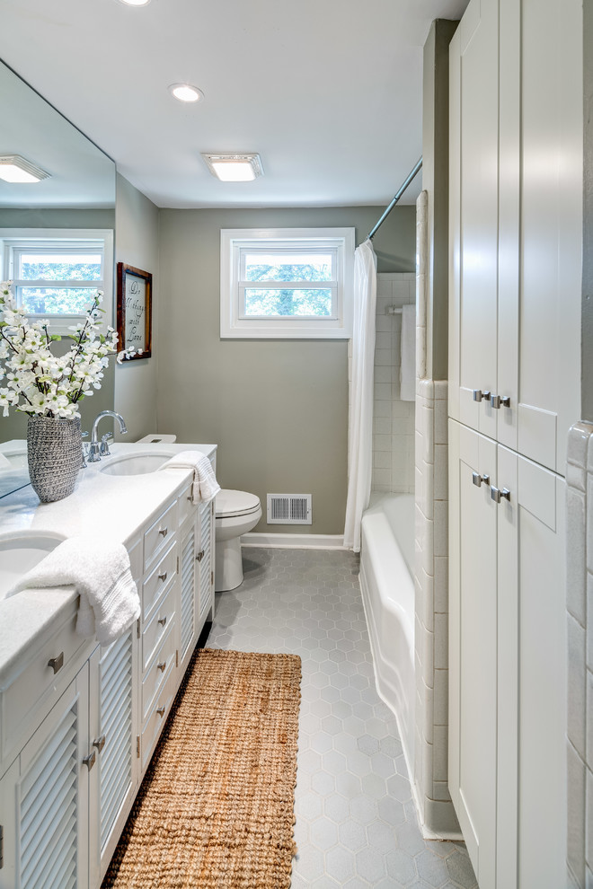 Modelo de cuarto de baño principal tradicional pequeño con puertas de armario blancas, bañera encastrada, combinación de ducha y bañera, paredes beige, suelo gris, ducha con cortina y encimeras blancas