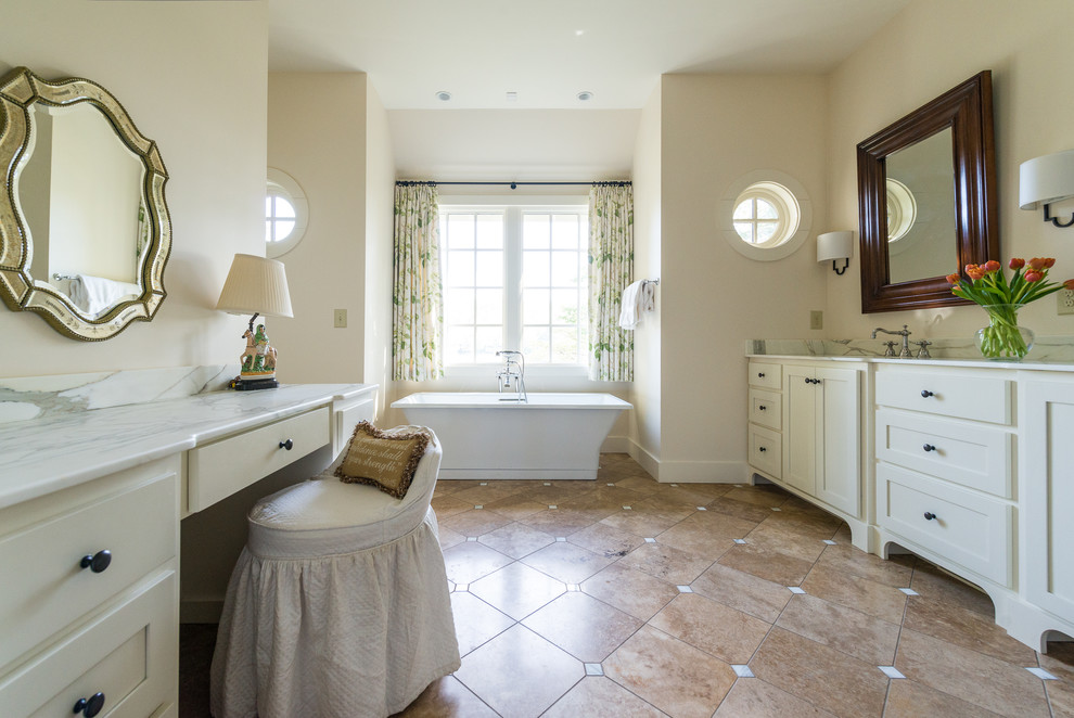 Imagen de cuarto de baño tradicional con armarios con paneles lisos, encimera de mármol, baldosas y/o azulejos blancos, puertas de armario blancas y bañera exenta