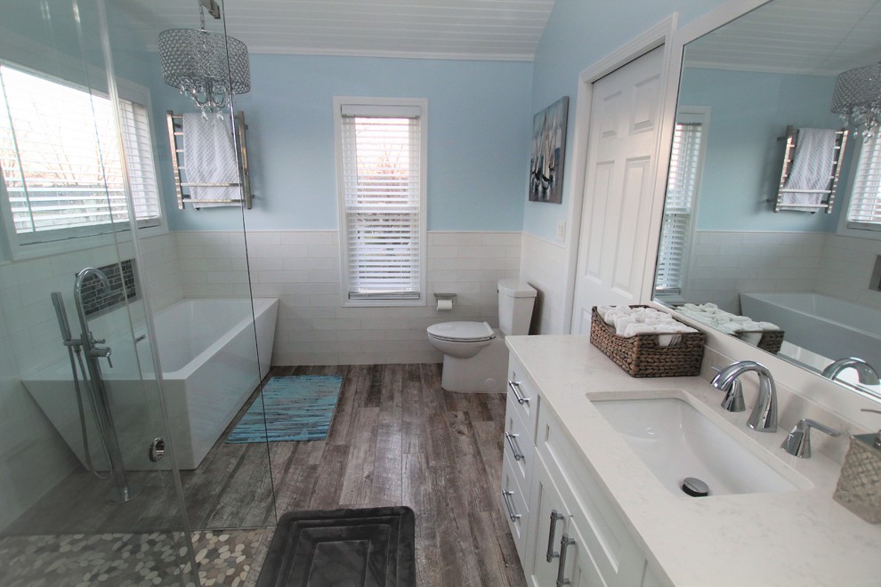 Design ideas for a medium sized classic ensuite bathroom in Atlanta with shaker cabinets, white cabinets, a freestanding bath, a built-in shower, a two-piece toilet, white tiles, ceramic tiles, blue walls, porcelain flooring, a submerged sink, engineered stone worktops, grey floors and a sliding door.