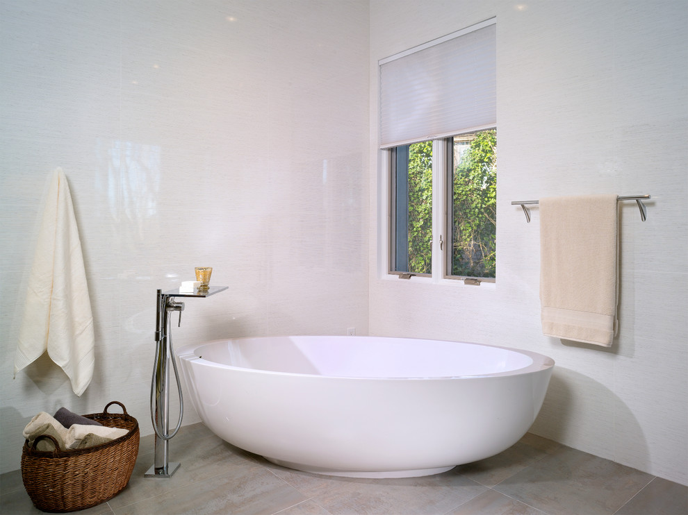 Inspiration for a large contemporary ensuite bathroom in Atlanta with flat-panel cabinets, medium wood cabinets, a wall mounted toilet, white tiles, white walls, a freestanding bath, a built-in shower, porcelain tiles, porcelain flooring, a submerged sink and engineered stone worktops.