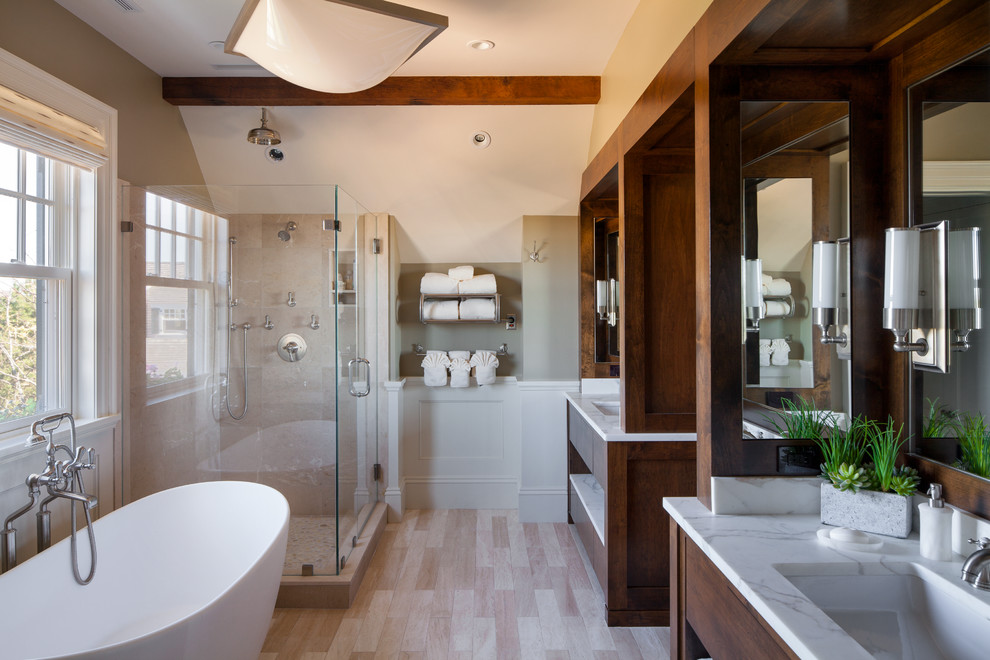 Exemple d'une grande salle de bain principale bord de mer en bois foncé avec un lavabo encastré, un placard à porte plane, un plan de toilette en marbre, une baignoire indépendante, une douche à l'italienne, un mur beige, parquet clair, un carrelage beige et mosaïque.