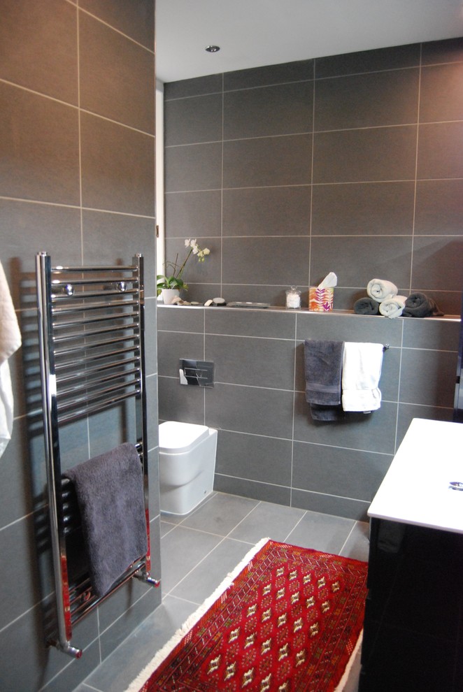 Bild på ett stort funkis badrum med dusch, med möbel-liknande, svarta skåp, en öppen dusch, en vägghängd toalettstol, grå kakel, keramikplattor, klinkergolv i keramik och ett integrerad handfat