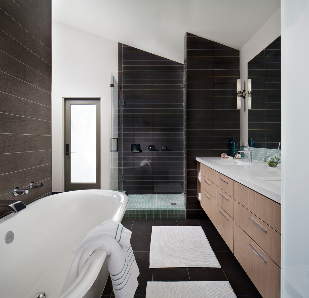 Idéer för ett mellanstort modernt en-suite badrum, med ett undermonterad handfat, släta luckor, skåp i ljust trä, ett fristående badkar, en dusch i en alkov, svart kakel, glaskakel, grå väggar, klinkergolv i keramik och bänkskiva i akrylsten