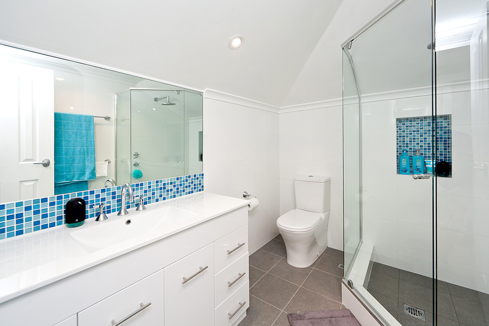 Bild på ett litet funkis en-suite badrum, med ett konsol handfat, släta luckor, vita skåp, en hörndusch, en toalettstol med hel cisternkåpa, vita väggar och klinkergolv i keramik