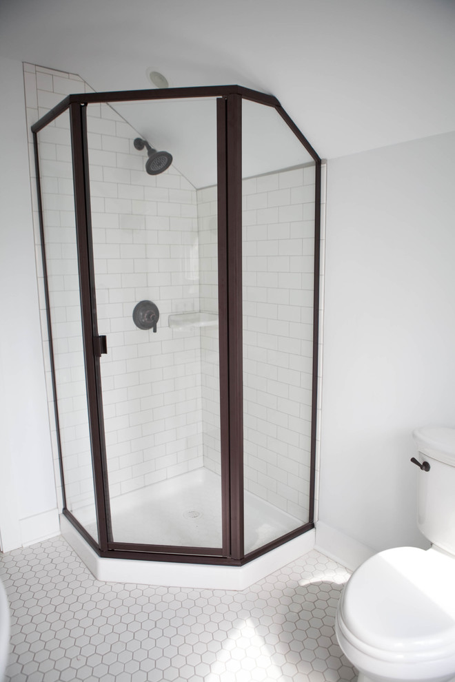 This is an example of a small traditional shower room bathroom in Kansas City with a wall-mounted sink, flat-panel cabinets, white cabinets, a corner shower, white tiles, ceramic flooring, white walls, white floors, a hinged door, a two-piece toilet and metro tiles.