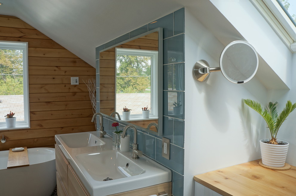 Idee per una stanza da bagno padronale scandinava di medie dimensioni con lavabo integrato, ante lisce, ante in legno chiaro, top in legno, vasca freestanding, doccia aperta, WC monopezzo, piastrelle blu, piastrelle di vetro, pareti bianche e pavimento con piastrelle in ceramica