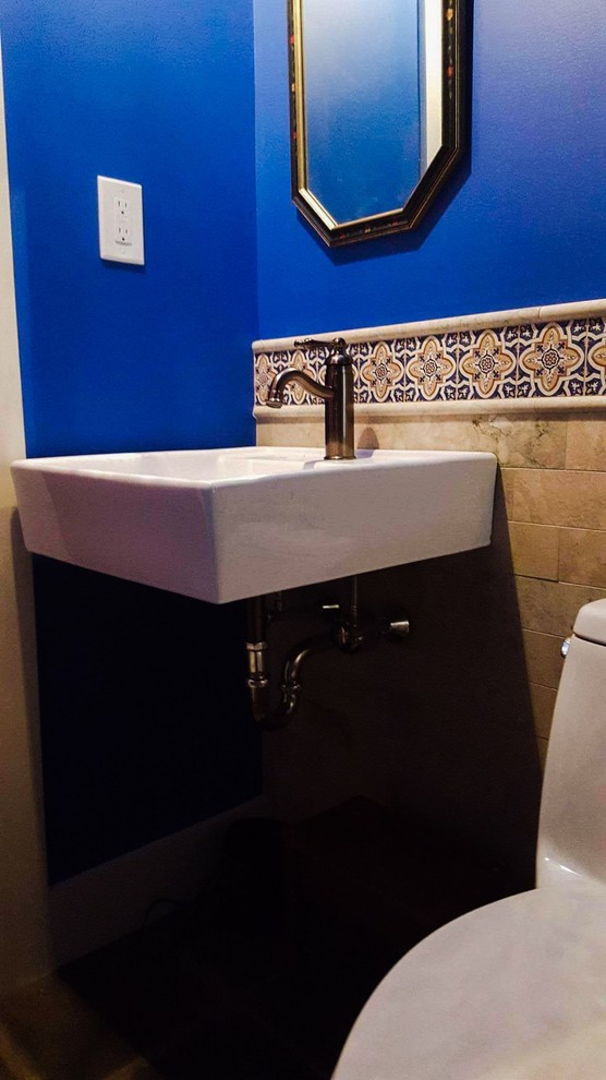 Exempel på ett litet medelhavsstil en-suite badrum, med ett fristående badkar, en toalettstol med hel cisternkåpa, beige kakel, stenkakel, blå väggar, klinkergolv i keramik, ett väggmonterat handfat och brunt golv