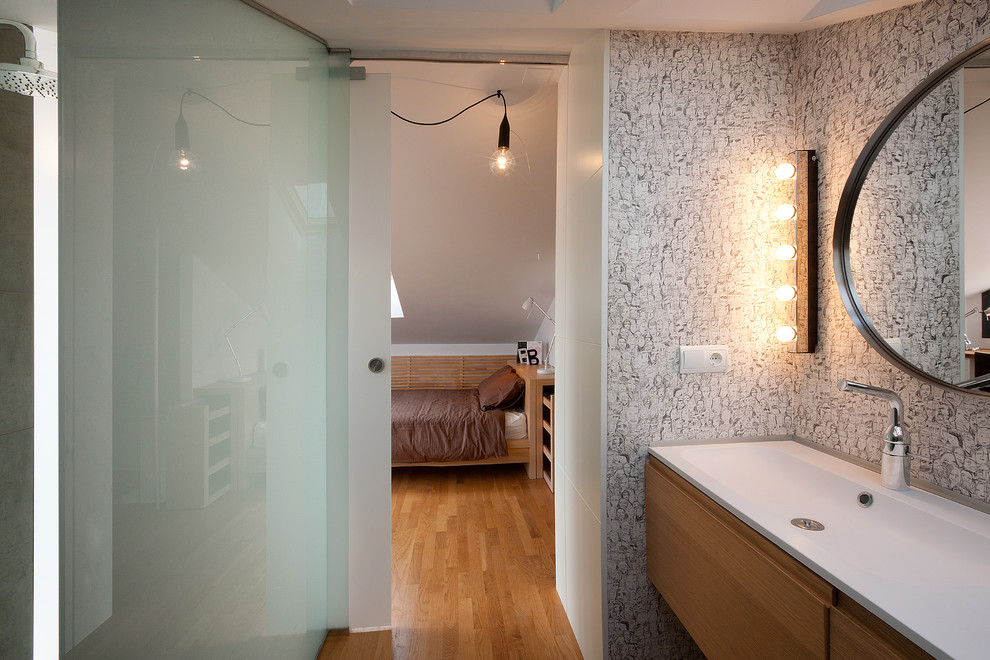 Foto på ett skandinaviskt badrum, med ett avlångt handfat, släta luckor och skåp i mellenmörkt trä