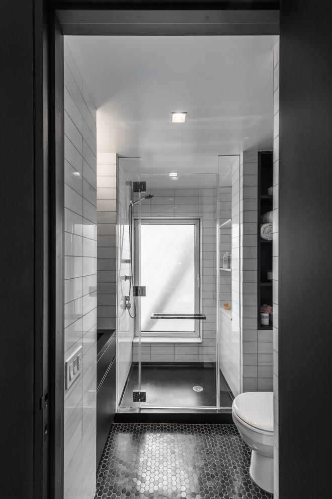 Inspiration for a small modern ensuite bathroom in New York with flat-panel cabinets, black cabinets, an alcove shower, a one-piece toilet, black and white tiles, stone tiles, white walls, marble flooring, an integrated sink and solid surface worktops.