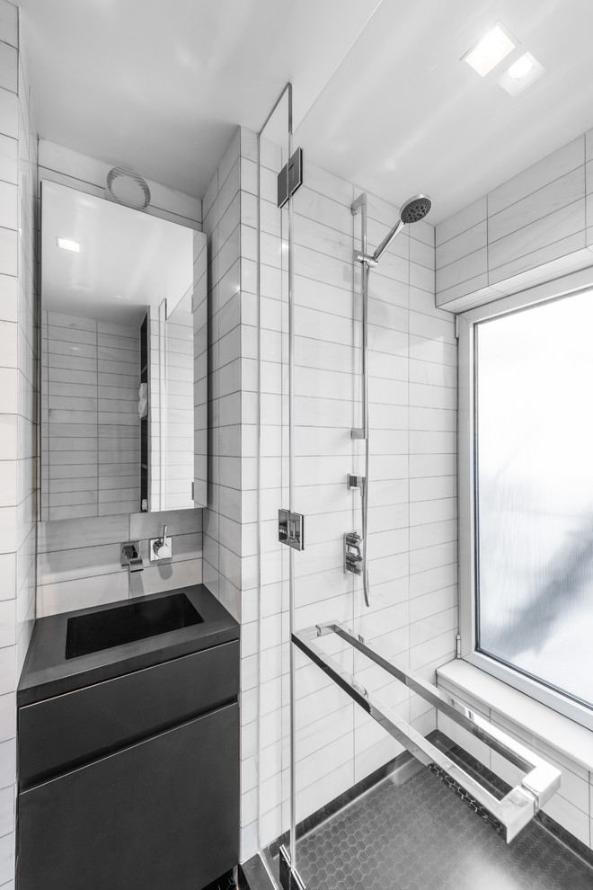 Immagine di una piccola stanza da bagno padronale minimalista con ante lisce, ante nere, doccia alcova, WC monopezzo, pistrelle in bianco e nero, piastrelle in pietra, pareti bianche, pavimento in marmo, lavabo integrato e top in superficie solida