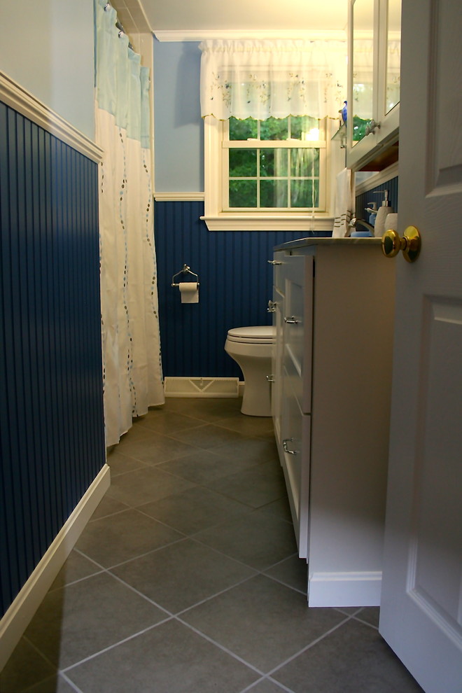 На фото: главная ванная комната среднего размера в классическом стиле с плоскими фасадами, белыми фасадами, мраморной столешницей, белой плиткой, керамогранитной плиткой, ванной в нише, душем над ванной, раздельным унитазом, монолитной раковиной, синими стенами и полом из керамогранита