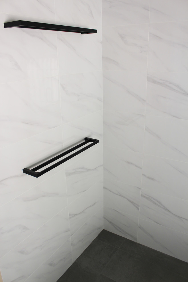 Example of a mid-sized trendy kids' white tile and porcelain tile porcelain tile and gray floor bathroom design in Perth with flat-panel cabinets, white cabinets, white walls, a vessel sink, marble countertops, a hinged shower door and gray countertops