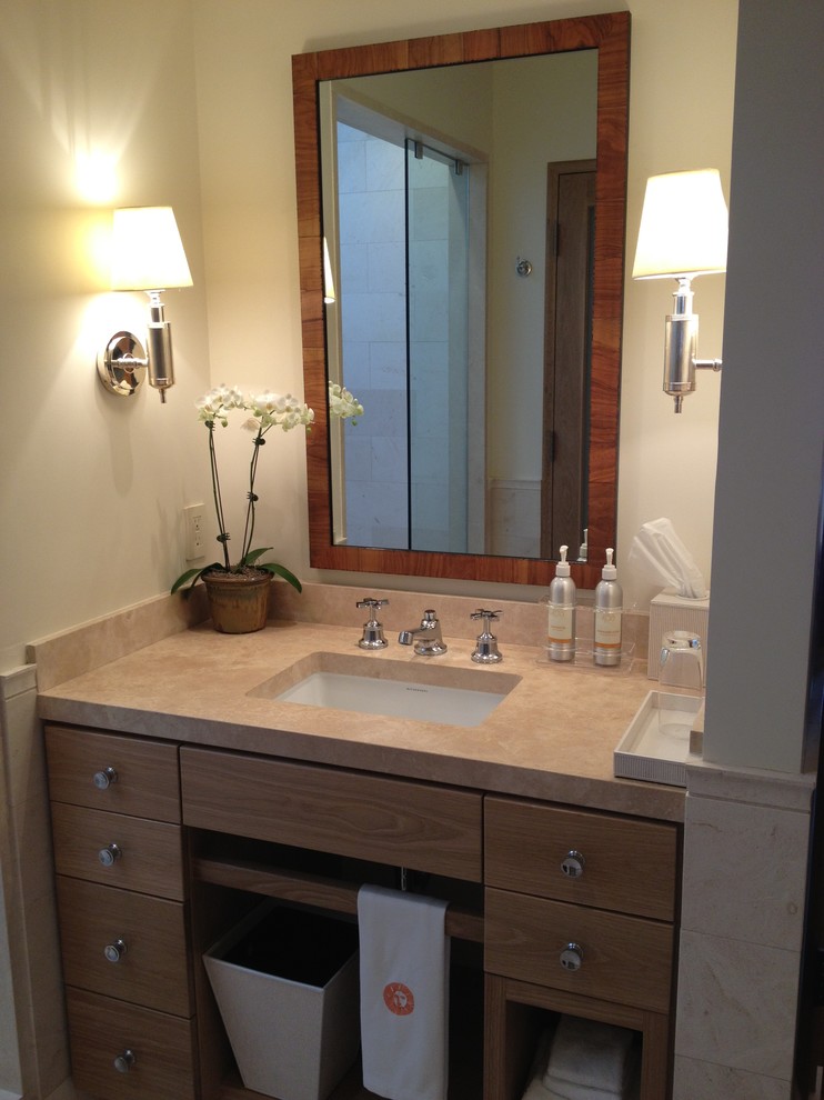 Cette image montre une salle de bain design en bois brun avec un lavabo suspendu, un placard à porte plane, un plan de toilette en calcaire, un carrelage beige, un carrelage de pierre et un mur beige.