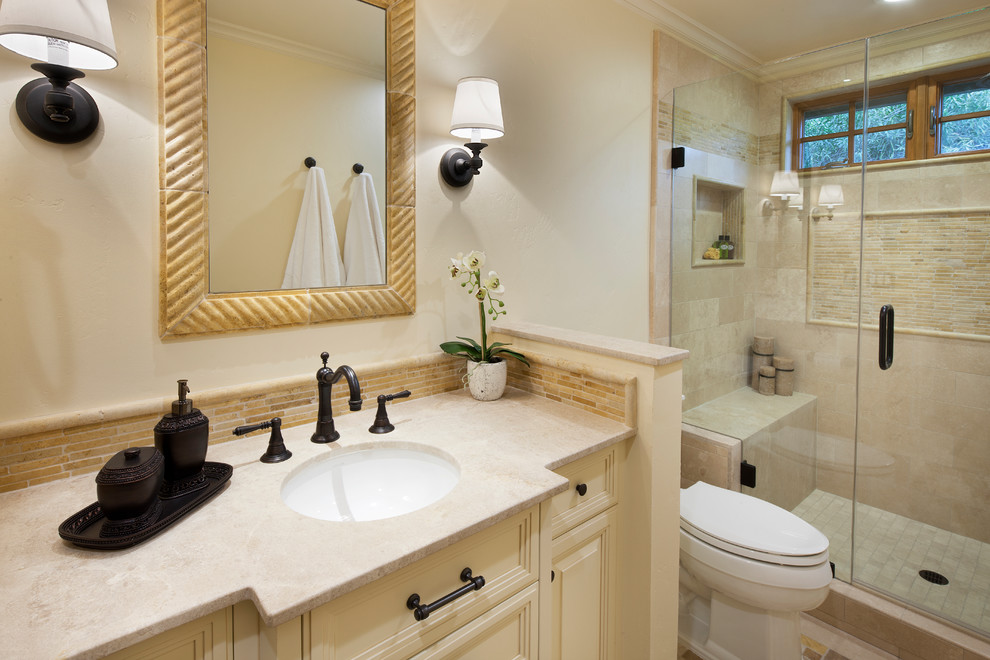 Idéer för små lantliga badrum med dusch, med möbel-liknande, gula skåp, en dusch i en alkov, flerfärgad kakel, stenkakel, bänkskiva i kalksten, en toalettstol med separat cisternkåpa, gula väggar, travertin golv och ett undermonterad handfat