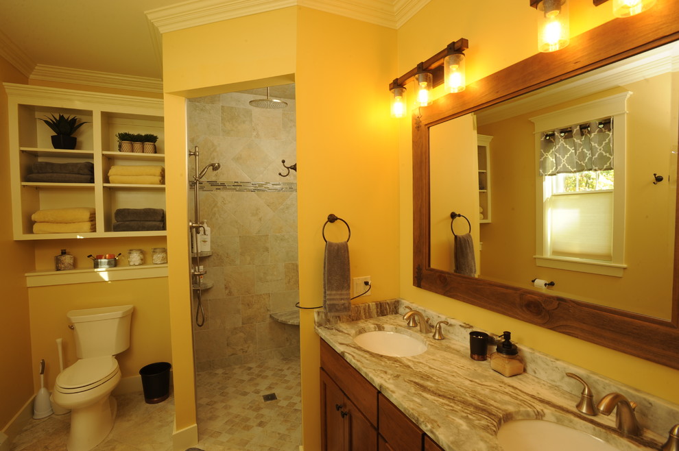 Lantlig inredning av ett mellanstort badrum, med skåp i mellenmörkt trä, en öppen dusch, stenkakel, gula väggar, ett undermonterad handfat och skåp i shakerstil