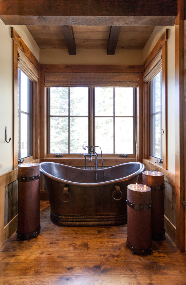 Idée de décoration pour une salle de bain chalet avec une baignoire indépendante et un sol en bois brun.