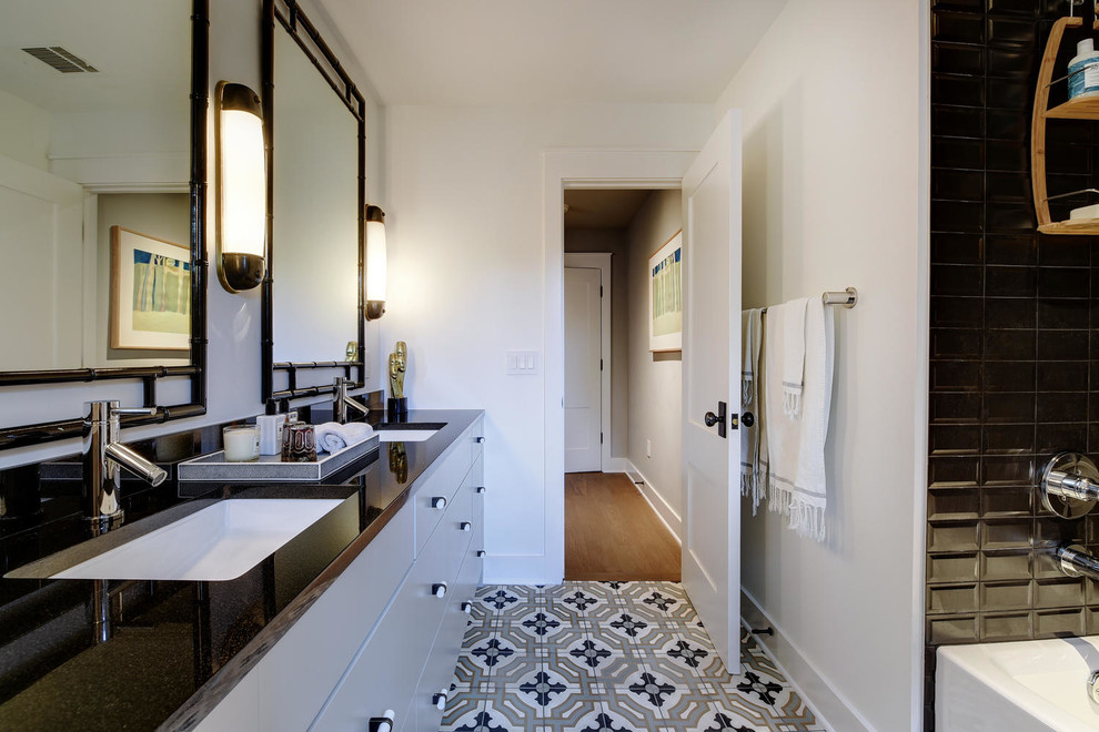 オースティンにある高級な広いトランジショナルスタイルのおしゃれなバスルーム (浴槽なし) (フラットパネル扉のキャビネット、グレーのキャビネット、アルコーブ型浴槽、シャワー付き浴槽	、黒いタイル、磁器タイル、白い壁、セラミックタイルの床、アンダーカウンター洗面器、御影石の洗面台、マルチカラーの床、シャワーカーテン) の写真