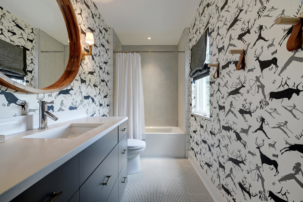 Medium sized classic family bathroom in Austin with flat-panel cabinets, grey cabinets, an alcove bath, a shower/bath combination, grey tiles, white tiles, mosaic tiles, multi-coloured walls, a submerged sink, white floors, a shower curtain, a one-piece toilet, mosaic tile flooring, engineered stone worktops and white worktops.