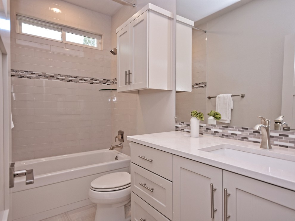 Exempel på ett mellanstort modernt badrum med dusch, med luckor med infälld panel, vita skåp, en dusch i en alkov, vit kakel, porslinskakel, grå väggar, klinkergolv i porslin, ett avlångt handfat och bänkskiva i kvarts