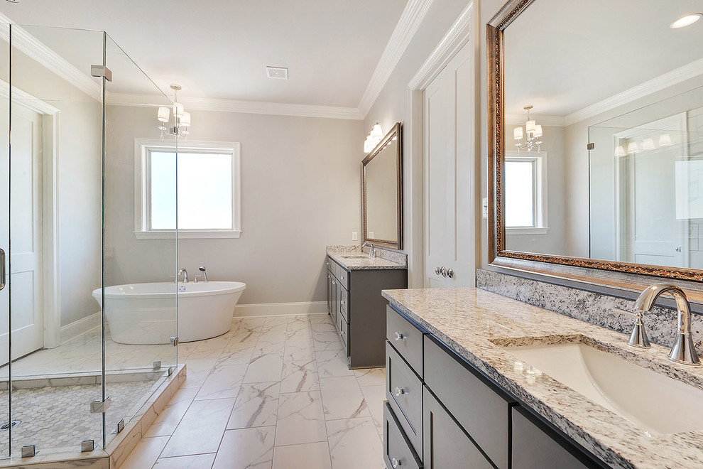 This is an example of a rural ensuite bathroom in New Orleans with shaker cabinets, grey cabinets, a freestanding bath, a double shower, a two-piece toilet, grey tiles, grey walls, ceramic flooring, a submerged sink, granite worktops, white floors and a hinged door.