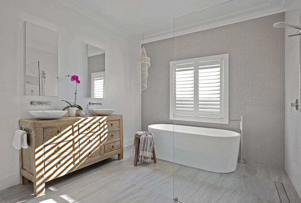 Идея дизайна: главная ванная комната среднего размера в современном стиле с светлыми деревянными фасадами, отдельно стоящей ванной, душевой комнатой, серой плиткой, стеклянной плиткой, белыми стенами, полом из керамогранита, настольной раковиной, серым полом и открытым душем
