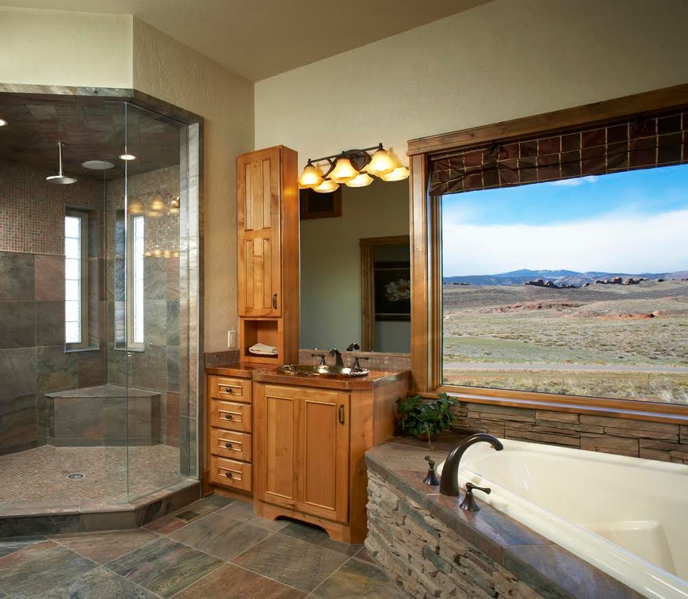 Exemple d'une grande salle de bain principale montagne en bois brun avec un placard à porte affleurante, une baignoire d'angle, une douche d'angle, un carrelage marron, un carrelage gris, un carrelage de pierre, un mur beige, un sol en carrelage de porcelaine, un lavabo posé et un plan de toilette en cuivre.