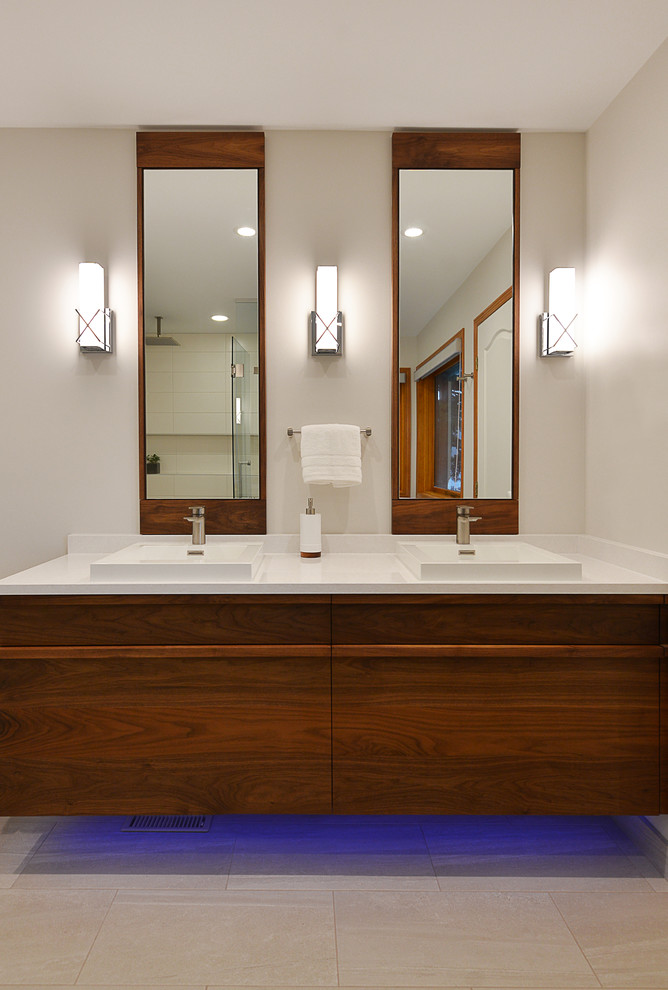 This is an example of a large contemporary ensuite bathroom in Vancouver with beaded cabinets, medium wood cabinets, a freestanding bath, a corner shower, a one-piece toilet, white tiles, ceramic tiles, white walls, pebble tile flooring, a vessel sink, engineered stone worktops, beige floors and a hinged door.