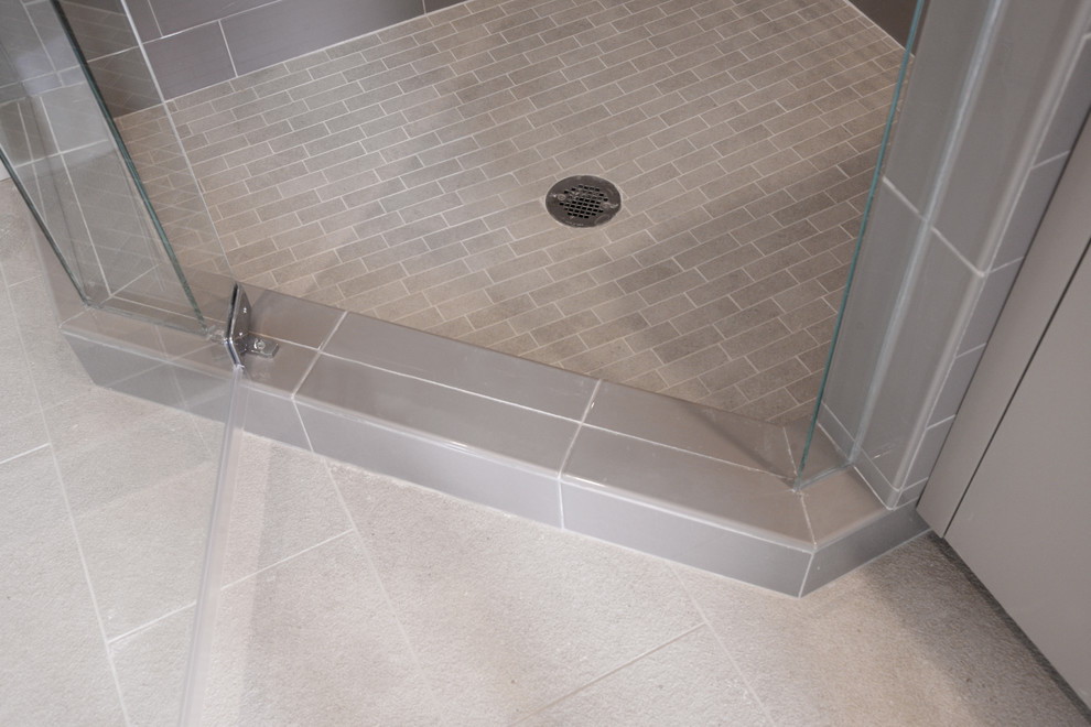 Cette image montre une salle d'eau design de taille moyenne avec une douche d'angle, un carrelage gris, des carreaux de céramique, un mur gris et un sol en carrelage de porcelaine.