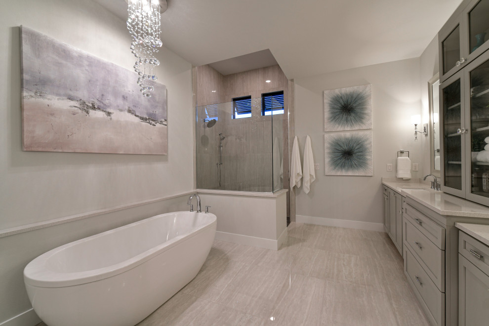 Klassisk inredning av ett mellanstort vit vitt en-suite badrum, med skåp i shakerstil, grå skåp, ett fristående badkar, en öppen dusch, en toalettstol med separat cisternkåpa, grå kakel, porslinskakel, grå väggar, klinkergolv i porslin, ett undermonterad handfat, bänkskiva i kvarts, vitt golv och med dusch som är öppen