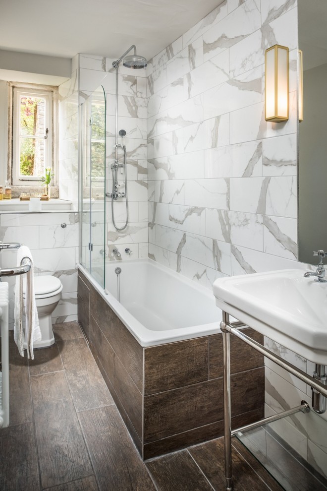 Inspiration för mellanstora klassiska badrum för barn, med ett platsbyggt badkar, en dusch/badkar-kombination, en toalettstol med separat cisternkåpa, flerfärgad kakel, vita väggar, mellanmörkt trägolv, ett väggmonterat handfat och brunt golv