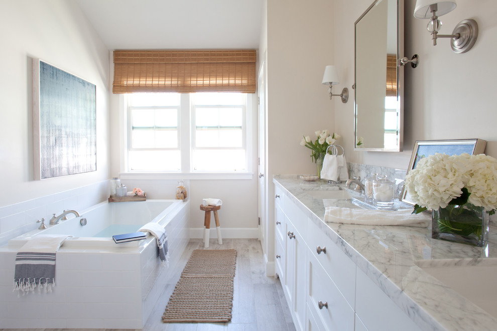 ロサンゼルスにあるトランジショナルスタイルのおしゃれな浴室 (シェーカースタイル扉のキャビネット、白いキャビネット、ドロップイン型浴槽、ベージュの壁、無垢フローリング、アンダーカウンター洗面器) の写真